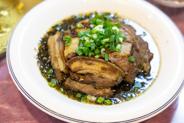 Serving of simple and authentic Sichuan cuisine of sliced pork belly with preserved vegetables topped with scallion