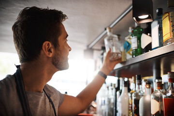 Pub, man and stock check with inventory management and bartender job at restaurant and small business. Bar, professional and shelf inspection of alcohol bottles for expiration date of product