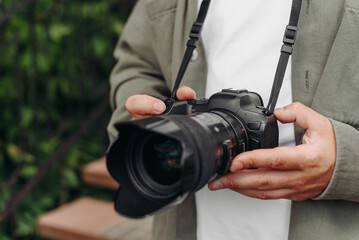 dslr camera in hands, young adult caucasian photographer in white t-shirt at work outdoors in sunny summer day