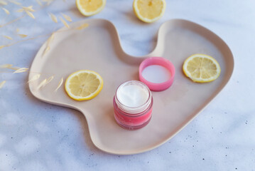 Vitamin C face cream with lemon slices on shadows background 