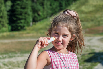 Toddler Girl applying sunscreen  in the summer mountain   .Spf stick 