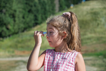 Toddler Girl applying sunscreen  in the summer mountain   .Spf stick 