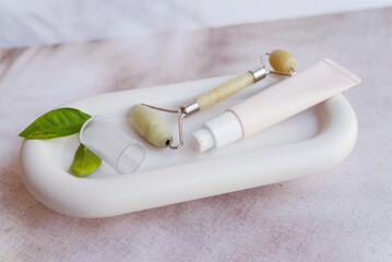 Anti-Age Face Cream and Jade Roller on Marble Plate