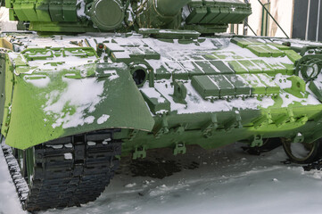 A tank with built-in protection against dynamic discharge. Conflicts, wars and fighting. Heavy weapons. The front part of a modern tank. A Russian tank covered with snow in winter.