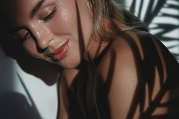 Young woman with blonde hair is holding a palm leaf  in sunlight © blackday