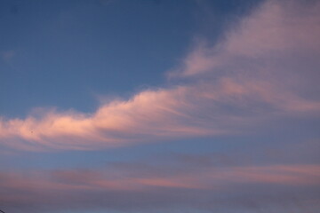 Clouds in the blue sky with white pink clouds on a summer evening on the eve of sunset