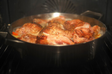 A pan of chicken is cooking in an oven
