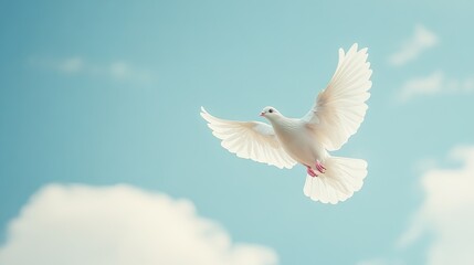 Fototapeta premium A white dove soars high in a clear blue sky, wings spread wide, symbolizing freedom and peace, with soft clouds in the background.