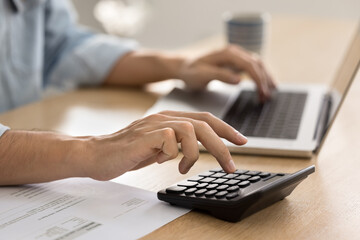 Cropped shot of male hands calculating money, income, expenses, fees, pushing buttons on...