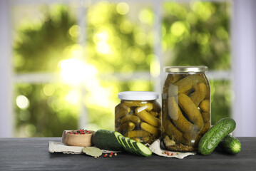Jars with pickled cucumbers on table indoors, space for text