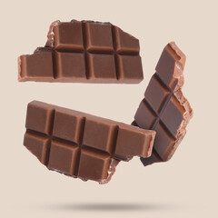 Pieces of sweet chocolate falling on beige background