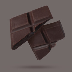Pieces of sweet chocolate falling on grey background