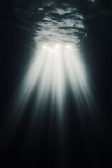 Obraz premium Light rays penetrating dark ocean water from surface. Underwater, deep sea concept. Image for marine documentary and ocean poster. With copy space.