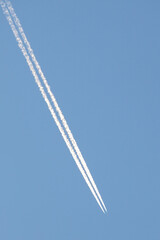 high in the blue sky a white trail of a flying plane