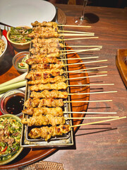 Delicious marinaded chicken stay sticks and sauce grilled on charcoal at the table in a restaurant in Bali Indonesia