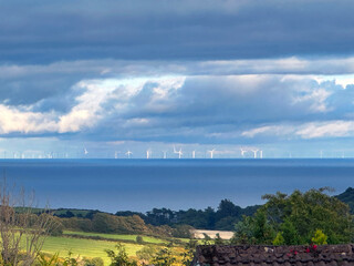 Obraz premium Distant wind farm on the English coast viewed across the Irish Sea and the Isle of Man