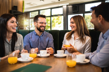Group of friends hanging out at the restaurant. They laugh, talk and drink coffee.