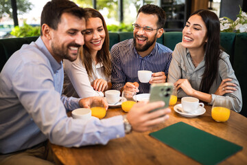 Group of friend met at the cafe. Looking at pictures on the phone. Having fun time together.