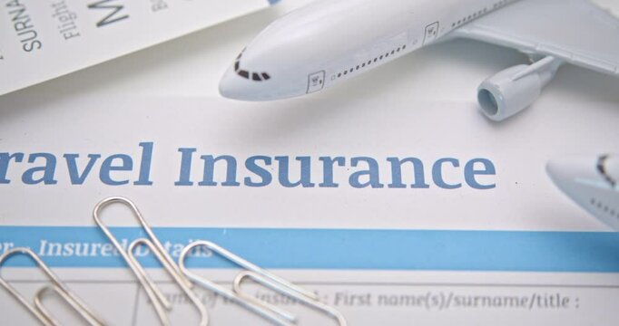 Travel insurance and service concept : Top view of travel insurance application form, a boarding pass, a passport and air plane. Travel insurance covers costs and losses associated with traveling.