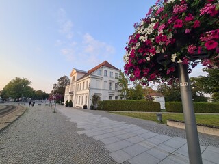 ein schöner Gehweg mit Blumen an einer Laterne auf der rechten Seite in Bad Doberan, Mecklenburg -...