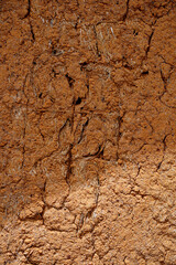 Structure wall of old mud house. Clay wall, surface texture. Close up. Vertical.