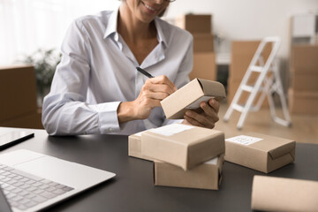 Businesswoman sit at desk with head of cardboard boxes, prepare ordered parcel goods to clients for...