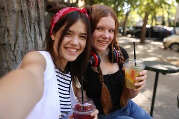 Happy teenage friends taking selfie in outdoor cafe