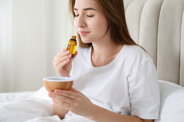 Fototapeta premium Woman with aroma diffuser and bottle of essential oil at home