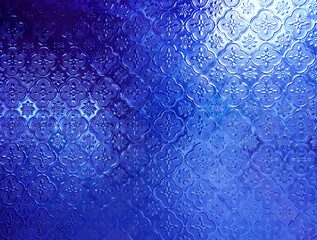 Background of light reflected from behind blue opaque glass with delicate etched floral design...