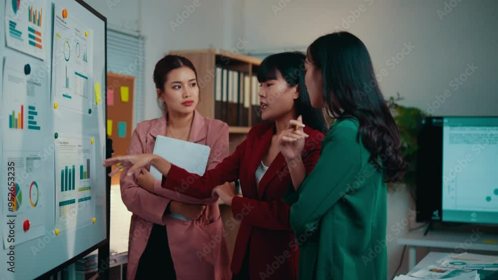 Poster three asian businesswomen are having a discussion about marketing strategy. they are using charts an