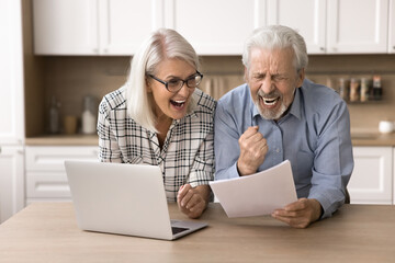 Happy aged couple read letter, hold document, bank statement, feels excited by great news, receive notice of loan repayment, money back, gesturing with joy. Celebrate financial success, pension growth
