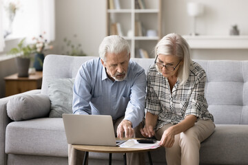 Serious couple sit on sofa, count monthly expenses, check mortgage payments, busy in finances...