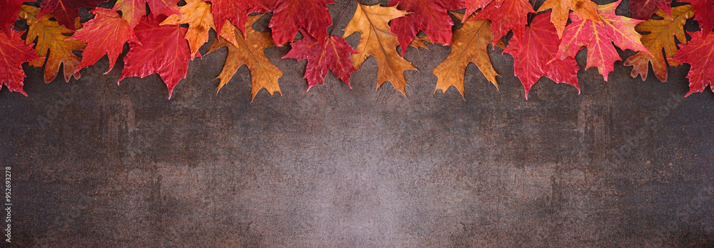 Poster colorful autumn leaves top border over a dark stone banner background. overhead view with copy space