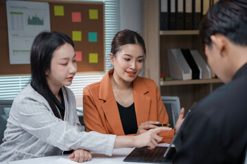 Two businesswomen and a businessman working together in the office, brainstorming and discussing a project