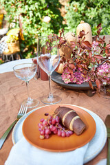Fall table setting with pumpkins and leaves and hydrangea in brown and burgundy tones