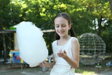 Portrait of smiling girl with sweet cotton candy in park
