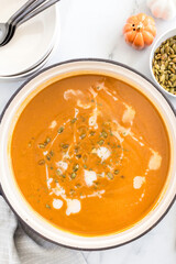 Butternut squash soup with cream and seeds in a pot