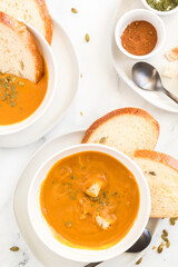 wo bowls of butternut squash soup with bread slices and spices