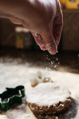 Hand dusting flour over gingerbread dough during holiday baking
