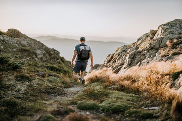 hiker with white backpack descends through rocky trail