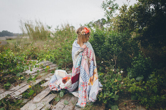 Little Girl standing in field with quilt