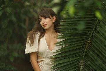 Naklejka premium Portrait of beautiful woman with palm tree leaf outdoors