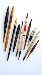 An artistic arrangement of different pen styles used to create autographs on a clean, light background