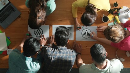 Top view of business team put graphic logo on meeting table with laptop and paper and start to design while explain idea. Manager explaining concept art while placed logo on meeting table. Symposium.