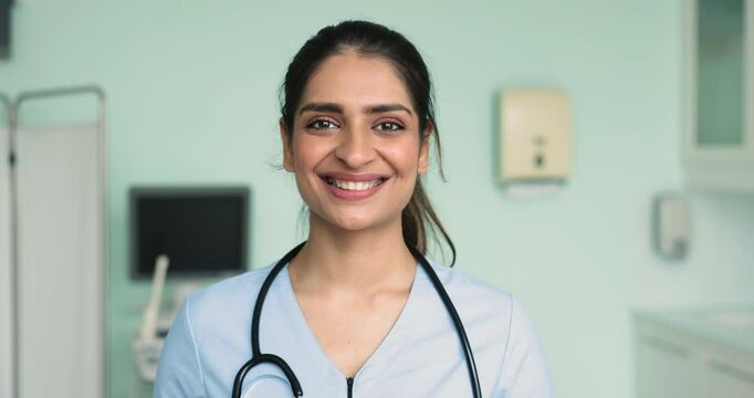 Head shot of attending physician, woman nurse, cardiologist in blue uniform posing for camera in hospital office, close up. Portrait of professional medical worker, private clinic general practitioner