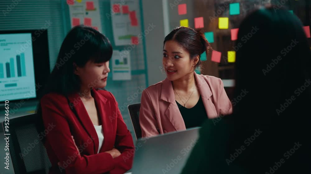 Poster three asian businesswomen engage in a meeting, discussing various points. two of them express disagr