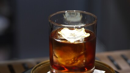 Closeup cocktail whiskey in Old fashioned with cube ice decorated dried sliced apple on top making special drink list, advertisement focusing alcohol refreshing showcase copy space at club. Vinosity.