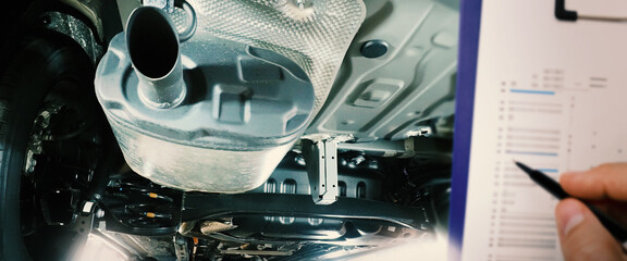 Under car exhaust pipe and suspension. Automotive mufflers. Inspection of car for Defects. Metal fittings and pipes for the muffler. Suspension elements and exhaust system. Auto parts and car service