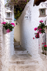 White stone stairs in the Turkish city of Marmaris. Pink flowers in pots hang on white walls