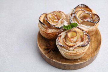Freshly baked apple roses with mint on light grey table, closeup. Space for text
